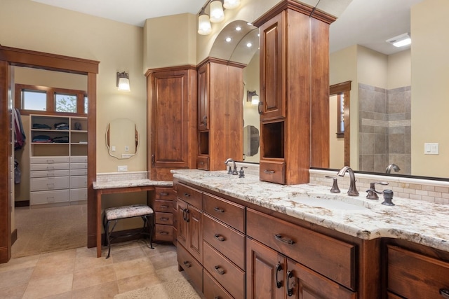 bathroom with double vanity, tile patterned floors, tiled shower, and a sink