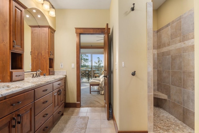bathroom with connected bathroom, a walk in shower, vanity, tile patterned floors, and baseboards