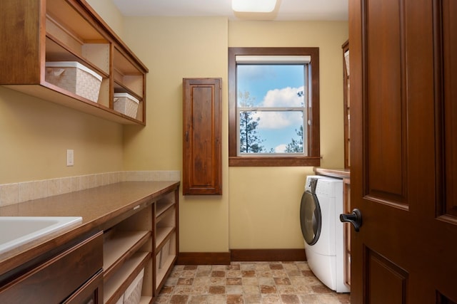clothes washing area featuring washer / clothes dryer, baseboards, a sink, and cabinet space