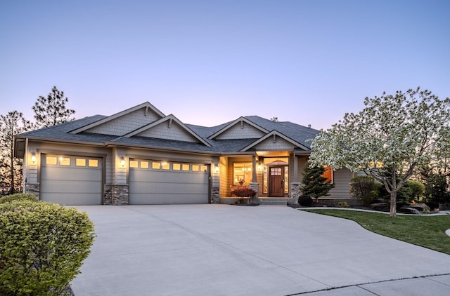 craftsman-style house featuring roof with shingles, an attached garage, driveway, and stone siding