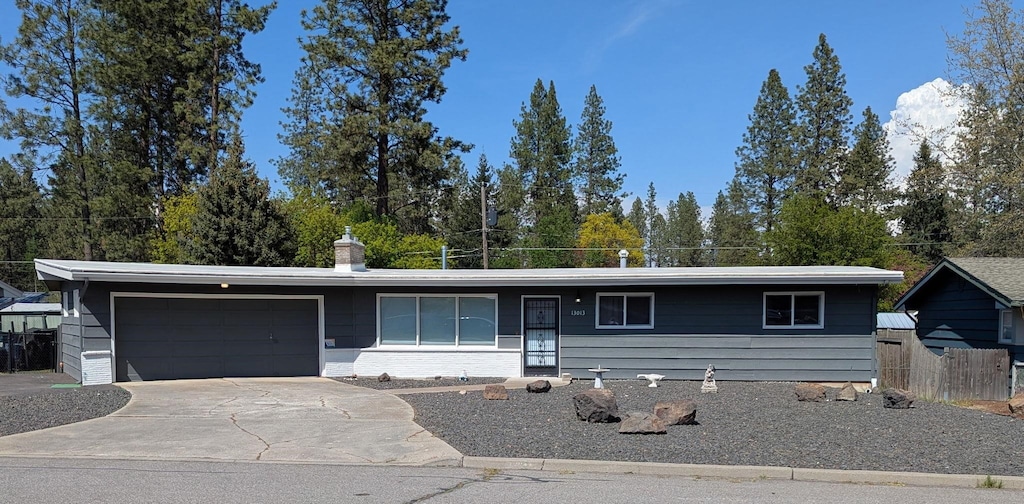ranch-style home with a garage, fence, and concrete driveway