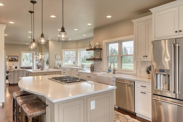 kitchen featuring appliances with stainless steel finishes, plenty of natural light, a sink, and a center island