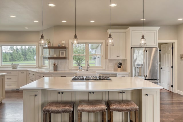 kitchen featuring appliances with stainless steel finishes, tasteful backsplash, a center island, light countertops, and dark wood-style floors