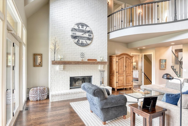 living room featuring visible vents, a fireplace, a high ceiling, stairway, and dark wood-type flooring