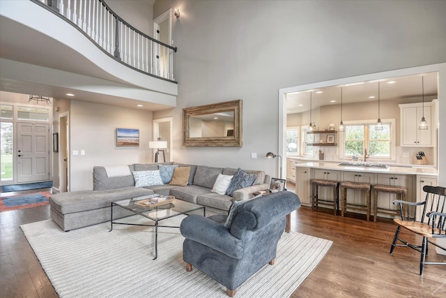 living room featuring recessed lighting, dark wood finished floors, and a towering ceiling