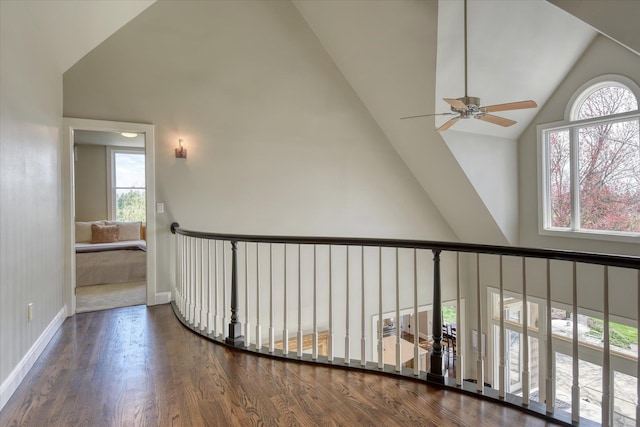 corridor with baseboards, high vaulted ceiling, and wood finished floors