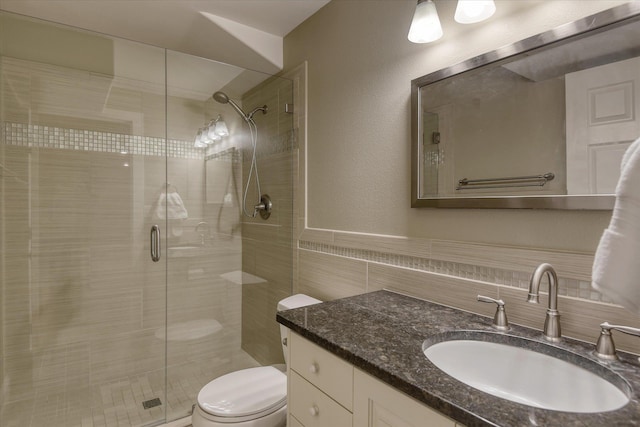 full bathroom with vanity, a stall shower, toilet, and tile walls
