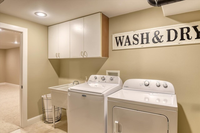 clothes washing area featuring light tile patterned flooring, washer and dryer, baseboards, a sink, and cabinet space