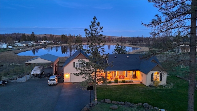 exterior space with driveway, a carport, a front lawn, a water view, and an attached garage