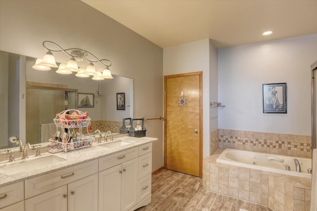 full bathroom with double vanity, a sink, a garden tub, and wood finished floors