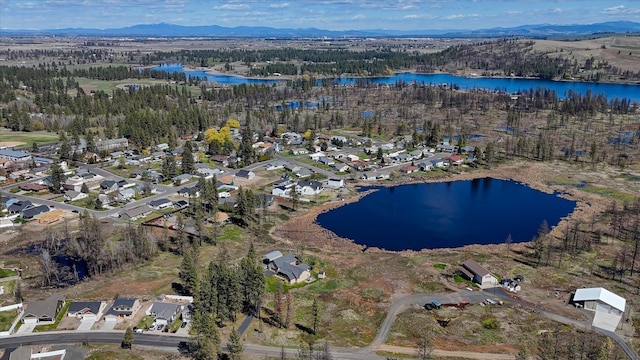 drone / aerial view featuring a water and mountain view, a residential view, and a wooded view