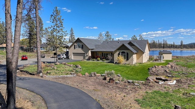 view of front facade with a water view, an attached garage, a front lawn, and aphalt driveway