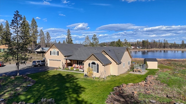 view of front of property featuring a porch, driveway, a garage, a front lawn, and a water view