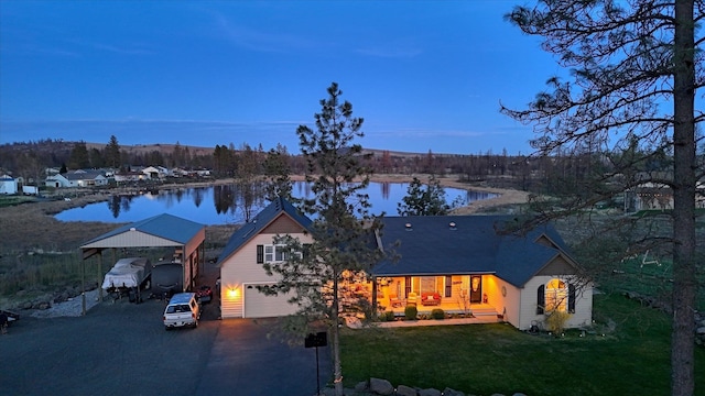 exterior space featuring a garage, a front yard, a water view, driveway, and a carport