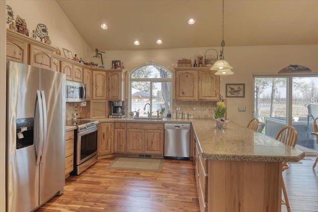 kitchen featuring a peninsula, a sink, appliances with stainless steel finishes, backsplash, and vaulted ceiling