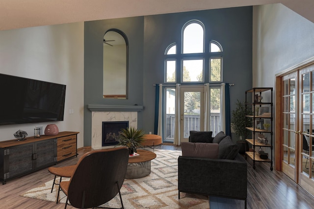 living area with a high ceiling, plenty of natural light, wood finished floors, and a fireplace
