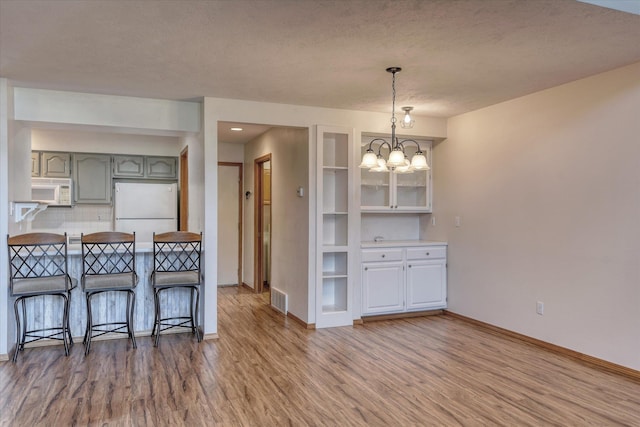 kitchen featuring a notable chandelier, white appliances, wood finished floors, and visible vents
