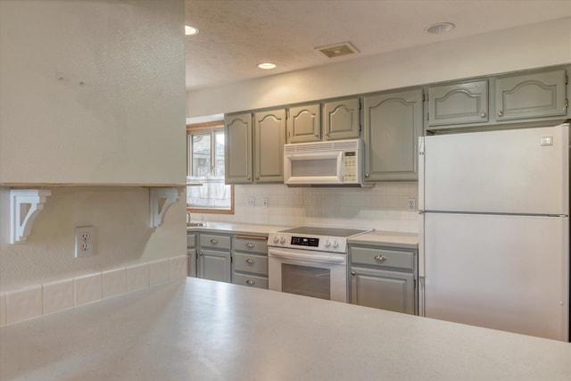kitchen with decorative backsplash, gray cabinets, light countertops, recessed lighting, and white appliances
