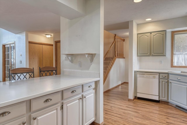 kitchen featuring light wood-style floors, white dishwasher, light countertops, gray cabinets, and tasteful backsplash