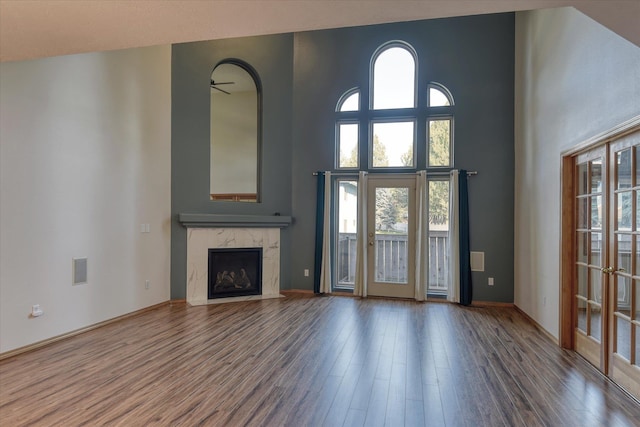 unfurnished living room with a high end fireplace, wood finished floors, and a healthy amount of sunlight