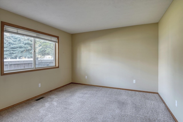 carpeted spare room featuring baseboards and visible vents
