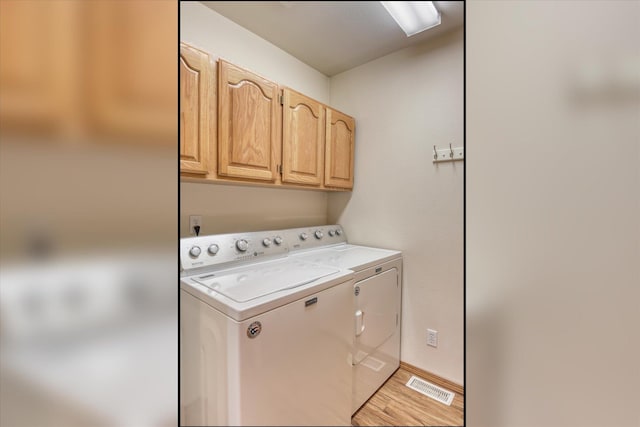 washroom with visible vents, light wood-style flooring, cabinet space, and washer and clothes dryer