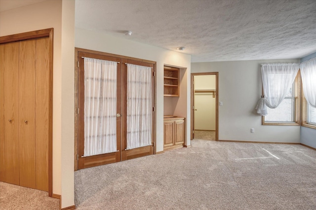 unfurnished bedroom featuring french doors, carpet flooring, and a textured ceiling