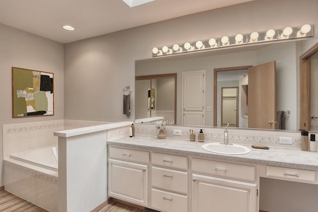 bathroom with wood finished floors, a bath, and vanity