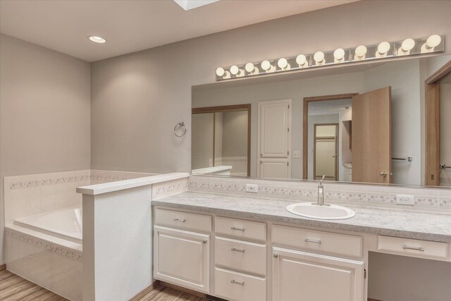 bathroom with vanity, a bath, toilet, and wood finished floors