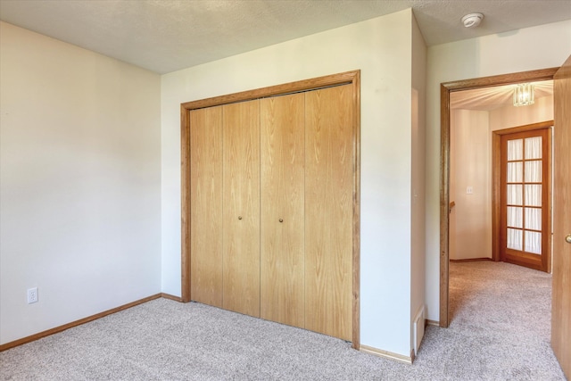 unfurnished bedroom featuring baseboards, light carpet, and a closet