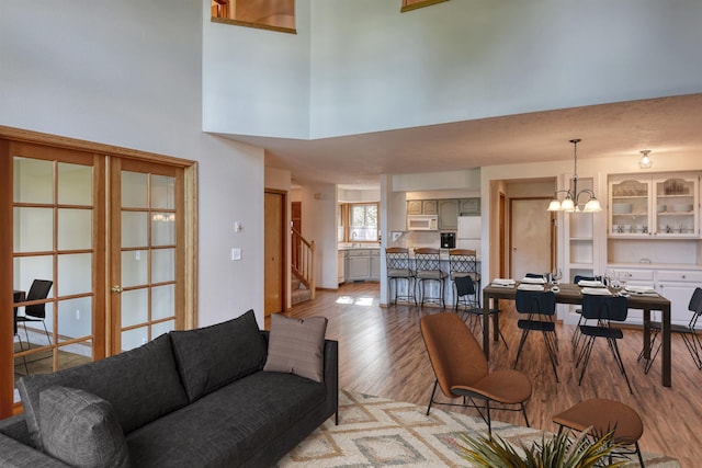 living area featuring a high ceiling, stairs, light wood-style flooring, and a chandelier