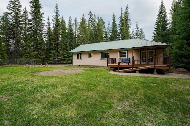back of property featuring crawl space, metal roof, a lawn, a wooden deck, and a wooded view