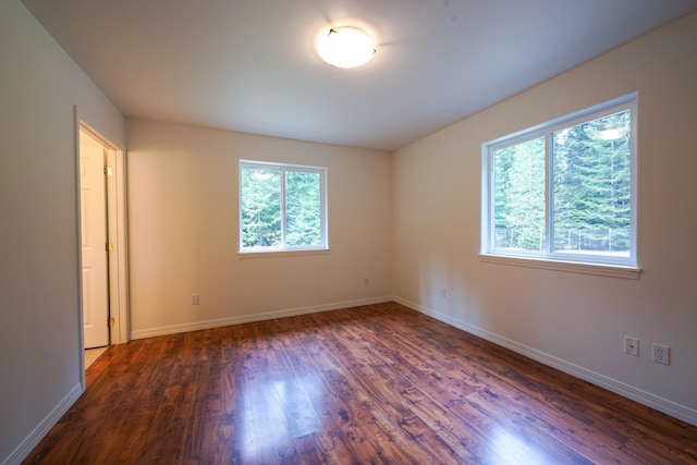 spare room featuring baseboards and dark wood-type flooring