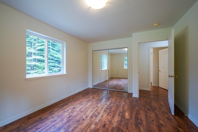 unfurnished bedroom featuring dark wood-type flooring, baseboards, and a closet