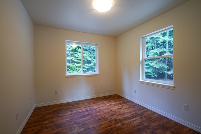 spare room featuring baseboards and dark wood-style flooring