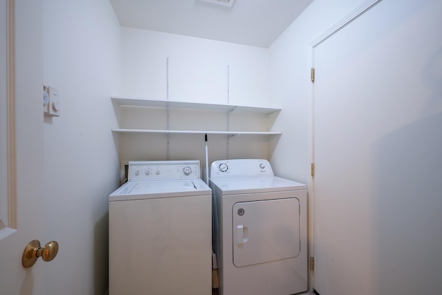 washroom with laundry area, visible vents, and washing machine and clothes dryer