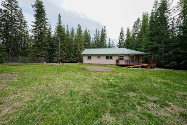 back of property with a wooden deck, a yard, and a forest view