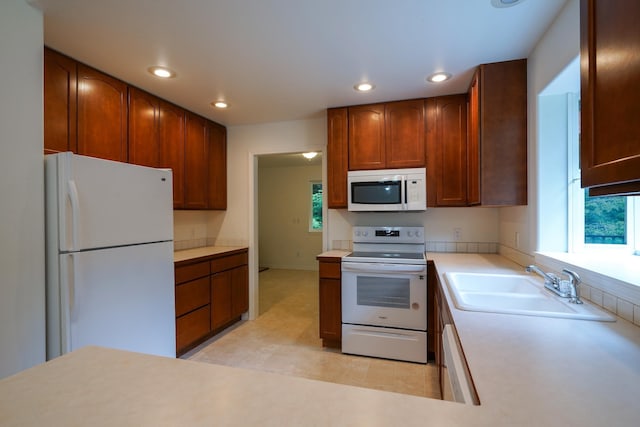 kitchen with recessed lighting, a sink, plenty of natural light, and white appliances