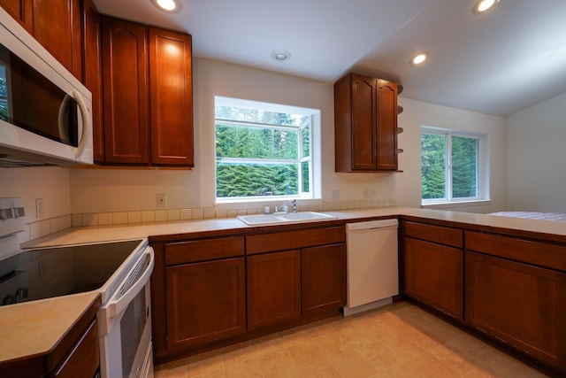 kitchen featuring white appliances, recessed lighting, a sink, and light countertops