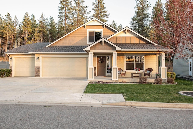 craftsman-style house with a front lawn, covered porch, roof with shingles, concrete driveway, and an attached garage