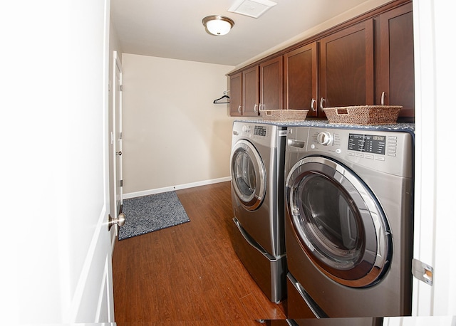 washroom featuring baseboards, cabinet space, washing machine and dryer, and dark wood finished floors