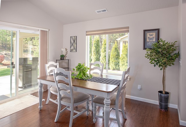 dining space featuring dark wood-style flooring, baseboards, visible vents, and lofted ceiling