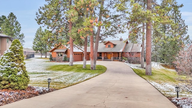 view of front of home with fence, stone siding, a front yard, a chimney, and concrete driveway