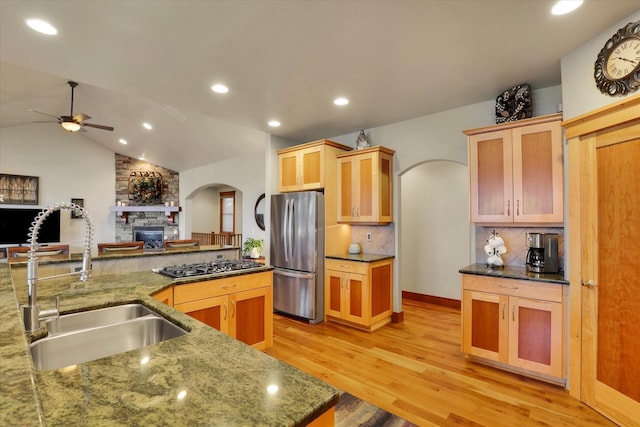 kitchen featuring freestanding refrigerator, a sink, arched walkways, gas stovetop, and a ceiling fan