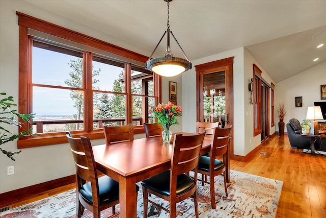 dining area with light wood-type flooring, baseboards, and lofted ceiling