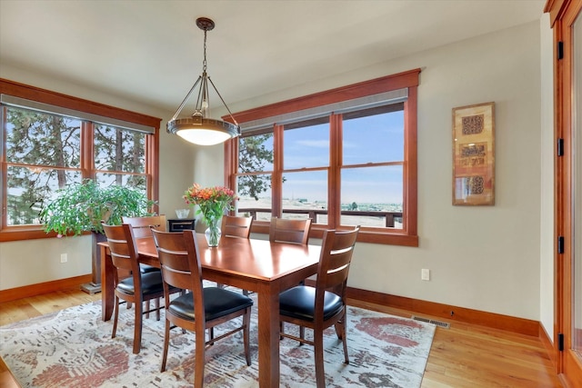 dining space with a water view, baseboards, visible vents, and light wood-style floors