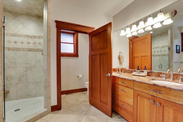 full bathroom with double vanity, a shower stall, a sink, tile patterned floors, and toilet