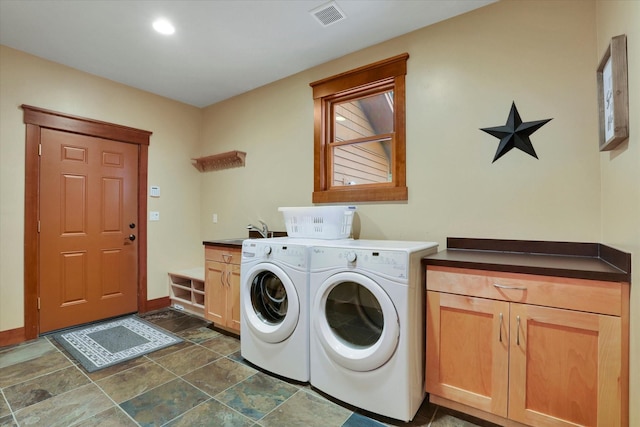 clothes washing area featuring visible vents, washing machine and dryer, stone finish flooring, a sink, and cabinet space
