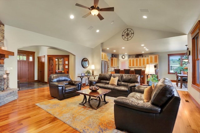 living room with a healthy amount of sunlight, light wood-style floors, ceiling fan, high vaulted ceiling, and arched walkways