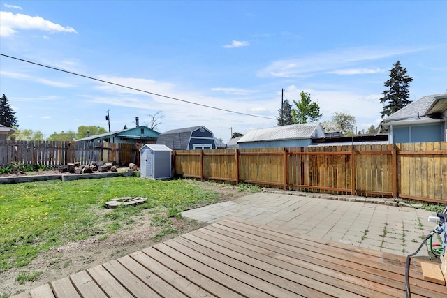 wooden deck featuring a fenced backyard, an outdoor structure, a yard, and a shed